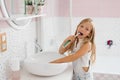 Cute child girl brushing her teeth in front of the bathroom mirror in the morning Royalty Free Stock Photo