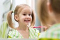 Cute child girl brushing teeth and looking in mirror in bathroom Royalty Free Stock Photo