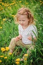 Cute child girl in dandelion wreath on spring flower field Royalty Free Stock Photo