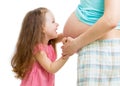 Cute child girl embracing pregnant mother belly