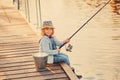 Cute child girl fishing from wooden pier on a lake. Family leisure activity during summer sunny day. little girl having fun by a