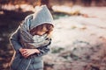 Cute child girl in grey knitted coat plays on the walk in winter forest