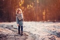 Cute child girl in grey knitted coat plays on the walk in winter forest Royalty Free Stock Photo