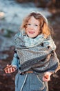 Cute child girl in grey knitted coat plays on the walk in winter forest Royalty Free Stock Photo