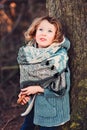 Cute child girl in grey knitted coat plays on the walk in winter forest Royalty Free Stock Photo