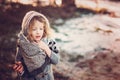 Cute child girl in grey knitted coat plays on the walk in winter forest Royalty Free Stock Photo