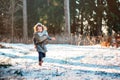 Cute child girl in grey knitted coat plays on the walk in winter forest Royalty Free Stock Photo