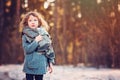 Cute child girl in grey knitted coat plays on the walk in winter forest Royalty Free Stock Photo