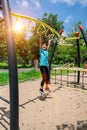 Cute child girl hanging hanging on monkey bars at the playground in park outdoor. Cute little girl having fun on summer garden