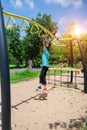 Cute child girl hanging hanging on monkey bars at the playground in park outdoor. Cute little girl having fun on summer garden