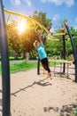 Cute child girl hanging hanging on monkey bars at the playground in park outdoor. Cute little girl having fun on summer garden