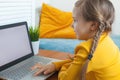 Cute child girl learning at home. Little girl using laptop with empty display with copy space