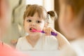 Cute kid girl looking at mirror using toothbrush cleaning teeth in bathroom every morning and night. Royalty Free Stock Photo