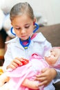 Cute child girl playing doctor with baby doll toy Royalty Free Stock Photo