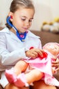 Cute child girl playing doctor with baby doll toy Royalty Free Stock Photo