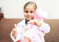Cute child girl playing doctor with baby doll toy Royalty Free Stock Photo