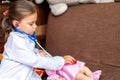 Cute child girl playing doctor with baby doll toy Royalty Free Stock Photo