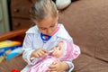 Cute child girl playing doctor with baby doll toy Royalty Free Stock Photo