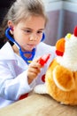 Cute child girl playing doctor with plush toy