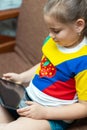 Cute child girl playing with tablet computer on the sofa at the home Royalty Free Stock Photo