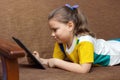 Cute child girl playing with tablet computer on the sofa at the home Royalty Free Stock Photo