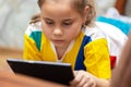 Cute child girl playing with tablet computer on the sofa at the home Royalty Free Stock Photo