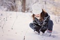 Cute child girl plays with snow in winter forest