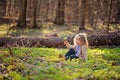 Cute child girl sitting in green leaves in early spring forest Royalty Free Stock Photo