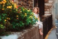 Cute child girl sitting on stone wall and smells flowers Royalty Free Stock Photo