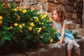 Cute child girl sitting on stone wall and smells flowers Royalty Free Stock Photo