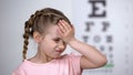 Cute child girl suffering headache, first myopia symptom, loss of eyesight