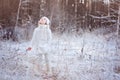 Cute child girl in white outfit on the walk in winter frozen forest