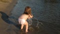 Cute child happily plays on the beach. baby splashing in the water. splashing water. happy child bathes in the sunset on