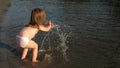 Cute child happily plays on the beach. baby splashing in the water. splashing water. happy child bathes in the sunset on