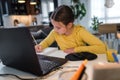 Cute child with headphones using laptop computer for online learning. Home school. Girl doing homework at home Royalty Free Stock Photo
