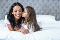 Cute child kissing her mother on the bed Royalty Free Stock Photo