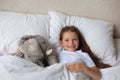 Cute child little girl wake up and lies in the bed with a toy elephant Royalty Free Stock Photo