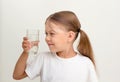 Cute child looking at glass of water in her hand on grey background Royalty Free Stock Photo