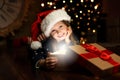 Cute child opening magic gift box near Christmas tree Royalty Free Stock Photo
