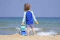 Cute child playing with car truck on sandy beach. Happy sailor boy on coast looking to the sea Royalty Free Stock Photo