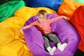 Cute child playing on colorful bean bag chairs