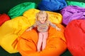 Cute child playing on colorful bean bag chairs