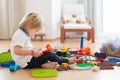 Cute child, playing with colorful toy blocks. Little boy building house of block toys sitting on the floor in sunny spacious Royalty Free Stock Photo