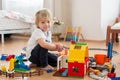 Cute child, playing with colorful toy blocks. Little boy building house of block toys sitting on the floor in sunny spacious Royalty Free Stock Photo