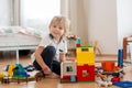 Cute child, playing with colorful toy blocks. Little boy building house of block toys sitting on the floor in sunny spacious Royalty Free Stock Photo