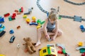 Cute child, playing with colorful toy blocks. Little boy building house of block toys sitting on the floor in sunny spacious Royalty Free Stock Photo