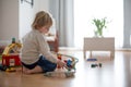 Cute child, playing with colorful toy blocks. Little boy building house of block toys sitting on the floor in sunny spacious Royalty Free Stock Photo