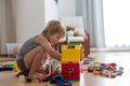 Cute child, playing with colorful toy blocks. Little boy building house of block toys sitting on the floor in sunny spacious Royalty Free Stock Photo