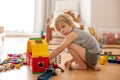 Cute child, playing with colorful toy blocks. Little boy building house of block toys sitting on the floor in sunny spacious Royalty Free Stock Photo