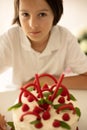 Cute child, preschool boy, celebrating birthday at home with homemade cake with raspberries, mint and candies